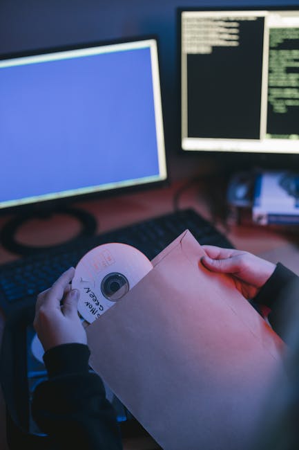 CD being inserted into a sleeve near computer displays with coding interface.